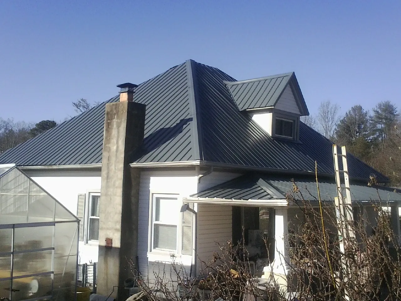Dark blue standing seam metal roof on a white farmhouse with dormer — Slate & Tile Roof Repair by Roofing Brothers in Glenham