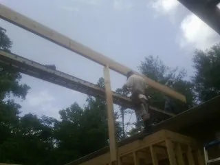 Carpenter setting a ridge beam over a new addition frame — Ice Dam Removal by Roofing Brothers in Glenham