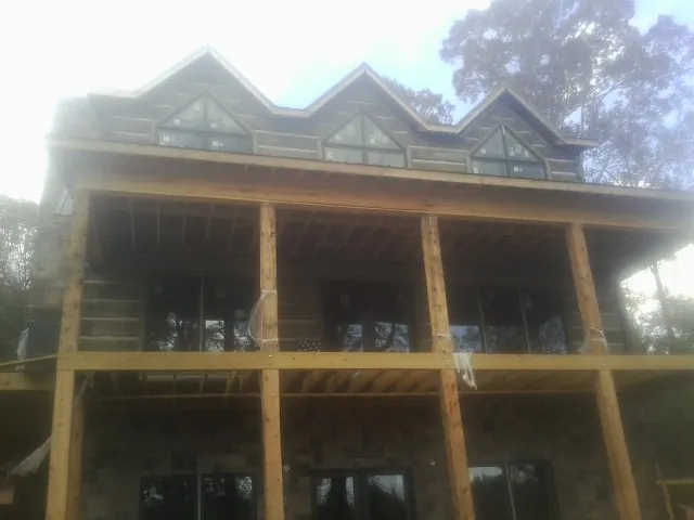 Dormers and porch framing on a large log home under construction — Roof Coating work by our crew in Glenham