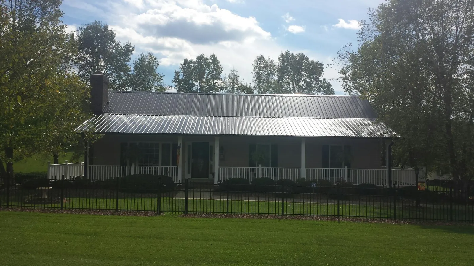 Gray metal roof on a brick ranch with a full width front porch — Gutter Guard Installation work by our crew in Glenham